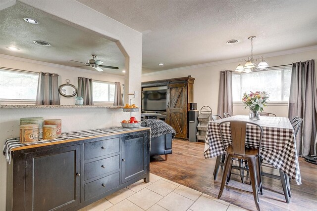 3554 Cromart Ct N, Fort Worth, TX 76133 - kitchen with a textured ceiling, crown molding, a ceiling fan, a chandelier, and light tile patterned flooring