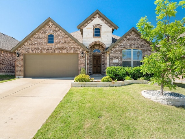 french country home featuring brick siding, a garage, driveway, a front lawn, and roof with shingles