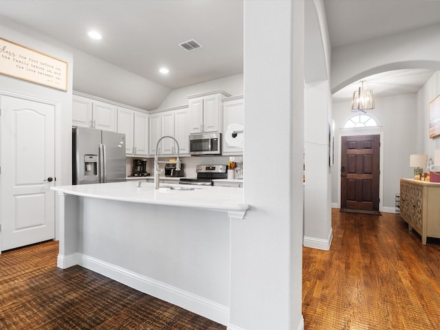 kitchen featuring appliances with stainless steel finishes, arched walkways, a sink, white cabinetry, and light countertops
