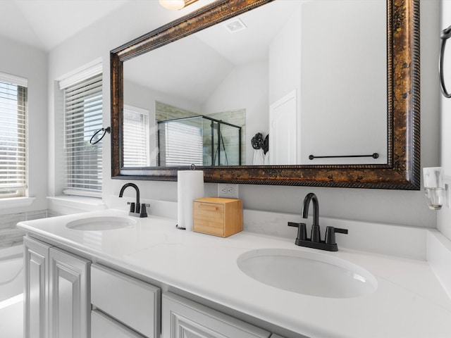 bathroom featuring a stall shower, double vanity, and lofted ceiling