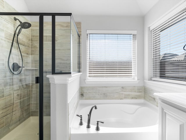 bathroom featuring plenty of natural light, a shower stall, a bath, and vanity