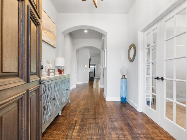 hallway featuring arched walkways, french doors, baseboards, and dark wood-style floors