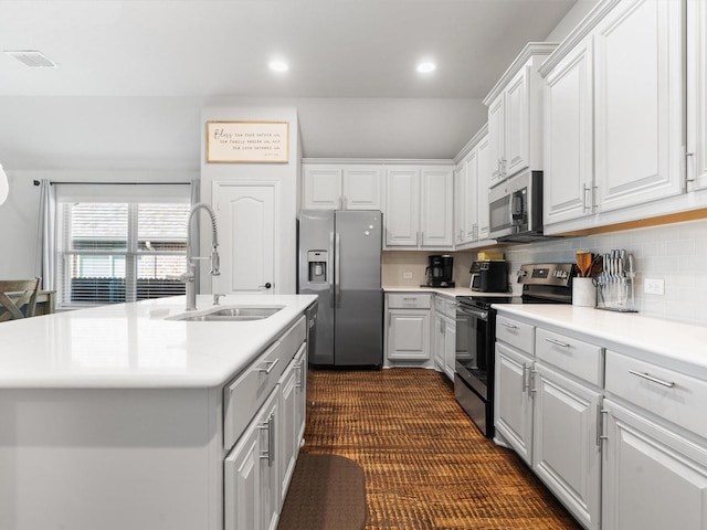 kitchen with appliances with stainless steel finishes, a sink, light countertops, white cabinetry, and recessed lighting