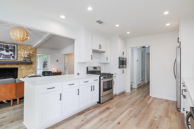 4940 Ashbrook Rd, Dallas, TX 75227 - kitchen with stainless steel appliances, light wood-style flooring, white cabinets, a fireplace, and recessed lighting