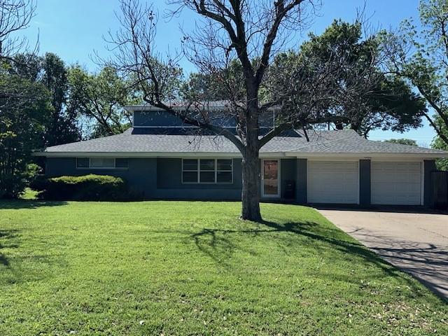view of front of house with an attached garage, a front lawn, concrete driveway, and roof with shingles