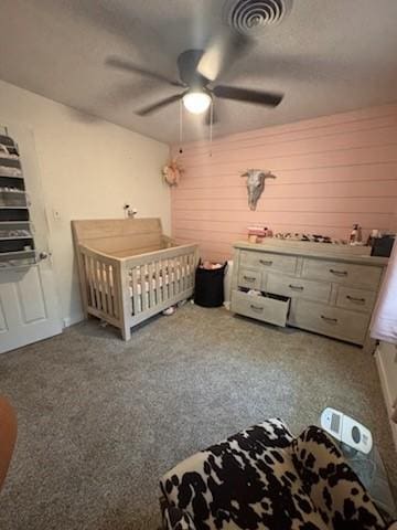 261 Barker St, Stephenville, TX 76401 - bedroom featuring a crib, ceiling fan, wood walls, and a textured ceiling