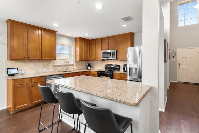 1915 Fairway Crossing Rd, Wylie, TX 75098 - kitchen featuring stainless steel appliances, a sink, dark wood-style floors, brown cabinetry, and recessed lighting