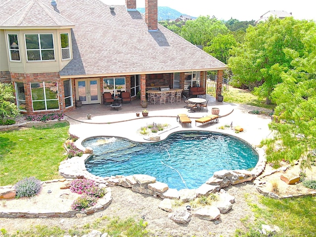 outdoor pool featuring french doors, a patio area, a bar, and a yard