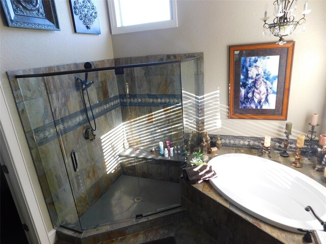 full bath featuring a garden tub, a shower stall, and a chandelier