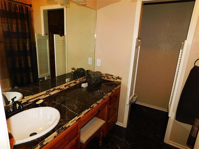 bathroom featuring toilet and double vanity