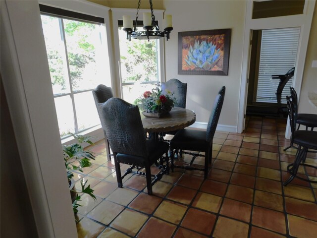 dining area with plenty of natural light, a chandelier, baseboards, and light tile patterned floors