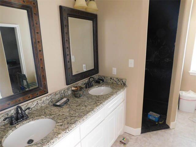 full bath with double vanity, tile patterned floors, and baseboards