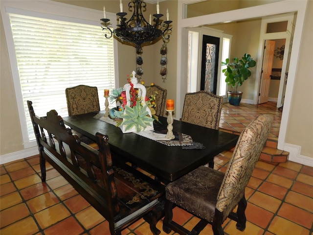 dining room with a chandelier, baseboards, and tile patterned floors
