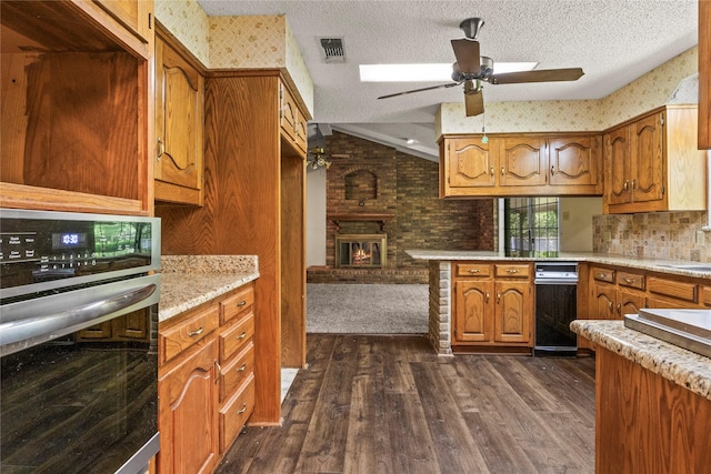 979 Rockdale, Sulphur Springs, TX 75482 - kitchen featuring oven, brown cabinets, ceiling fan, dark wood-type flooring, and a brick fireplace
