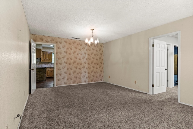 979 Rockdale, Sulphur Springs, TX 75482 - unfurnished room with a chandelier, carpet, a textured ceiling, and baseboards