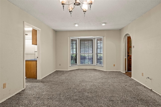 979 Rockdale, Sulphur Springs, TX 75482 - unfurnished room featuring arched walkways, a textured ceiling, carpet, a chandelier, and baseboards