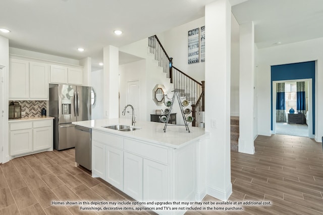 kitchen with light wood finished floors, a sink, stainless steel appliances, light countertops, and decorative backsplash