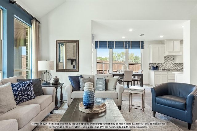 living room featuring light wood finished floors, plenty of natural light, vaulted ceiling, and recessed lighting