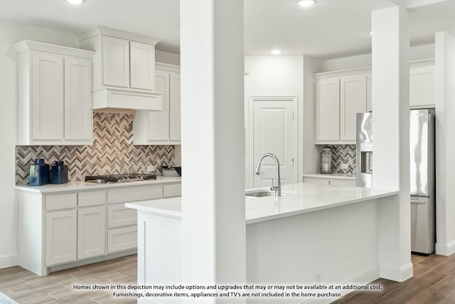 kitchen with light wood finished floors, a sink, white cabinetry, light countertops, and tasteful backsplash