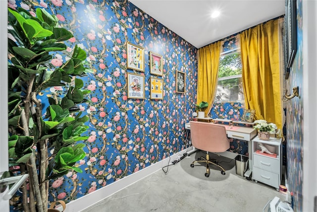 office area with wallpapered walls, baseboards, and concrete flooring