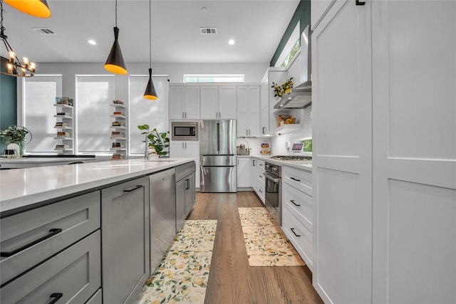 kitchen featuring stainless steel appliances, a sink, wood finished floors, pendant lighting, and recessed lighting