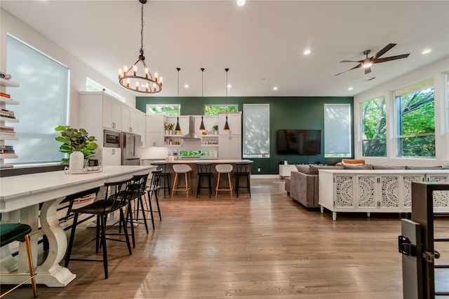 living room with wood finished floors, a chandelier, a ceiling fan, and recessed lighting