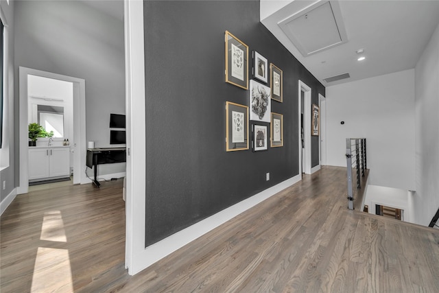 corridor with an upstairs landing, wood finished floors, baseboards, and recessed lighting