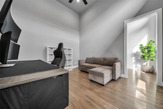 office with light wood-style floors, a ceiling fan, baseboards, and vaulted ceiling