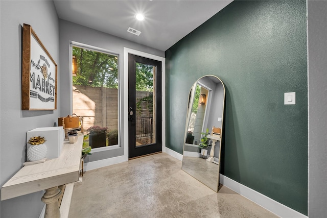 entryway featuring finished concrete floors, baseboards, and a textured wall
