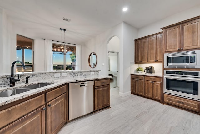 308 Pioneer Ct, Mclendon Chisholm, TX 75032 - kitchen featuring stainless steel appliances, a sink, arched walkways, light stone counters, and pendant lighting