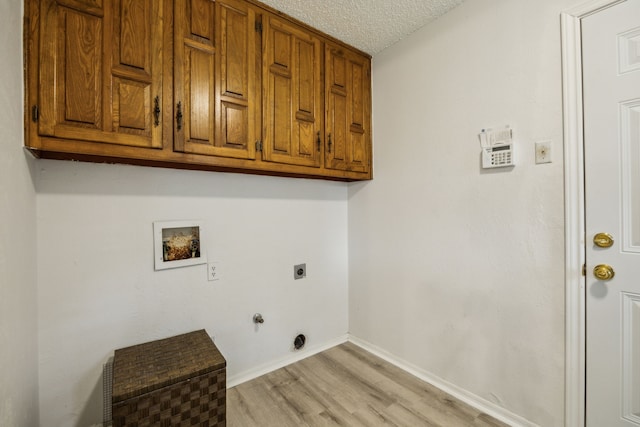 614 Willowbrook Cir, Duncanville, TX 75116 - clothes washing area featuring electric dryer hookup, washer hookup, light wood finished floors, cabinet space, and a textured ceiling