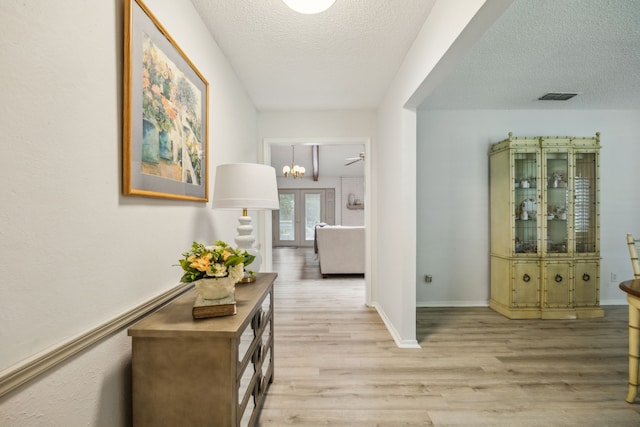 614 Willowbrook Cir, Duncanville, TX 75116 - hallway featuring light wood-style flooring, a textured ceiling, baseboards, and a chandelier