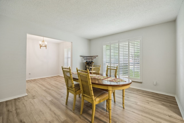 614 Willowbrook Cir, Duncanville, TX 75116 - dining area featuring light wood finished floors, a chandelier, a textured ceiling, and baseboards