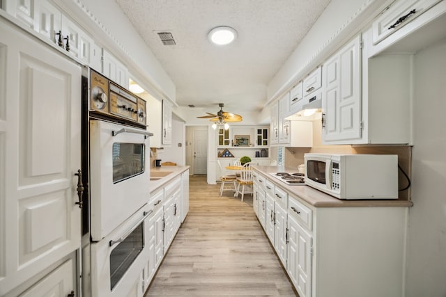 614 Willowbrook Cir, Duncanville, TX 75116 - kitchen with white appliances, light wood-style floors, white cabinetry, and a textured ceiling