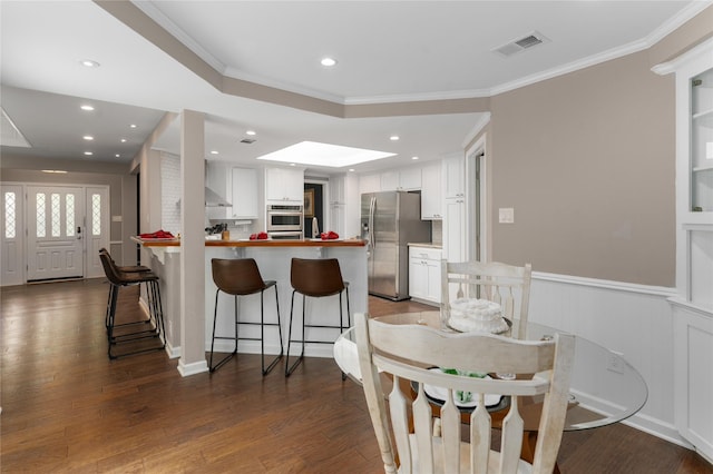 7610 Bantry Cir, Dallas, TX 75248 - kitchen with stainless steel appliances, wall chimney exhaust hood, a peninsula, white cabinets, and a breakfast bar
