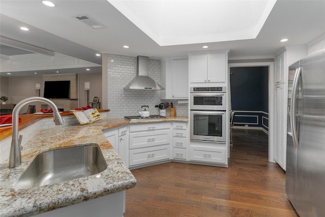 7610 Bantry Cir, Dallas, TX 75248 - kitchen featuring appliances with stainless steel finishes, wall chimney exhaust hood, a sink, dark wood-type flooring, and backsplash