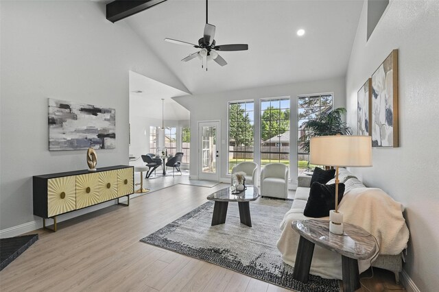 living area with high vaulted ceiling, beam ceiling, a ceiling fan, wood finished floors, and baseboards