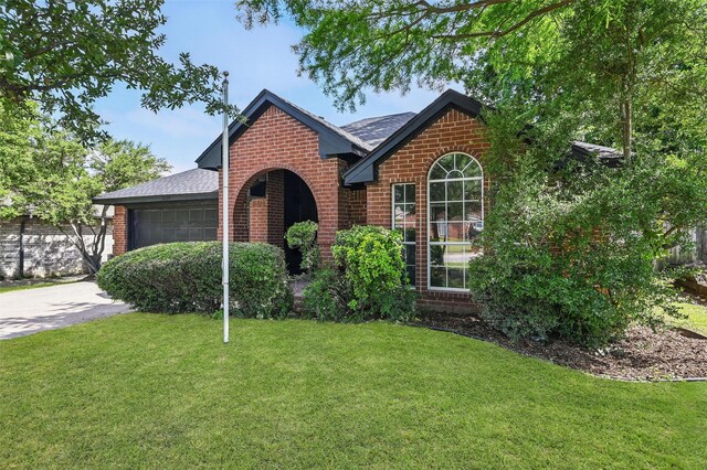 view of front of property featuring brick siding, a garage, a front lawn, and roof with shingles