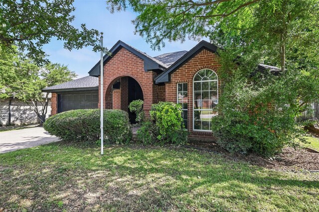 view of front of house with brick siding, a garage, a front lawn, roof with shingles, and concrete driveway