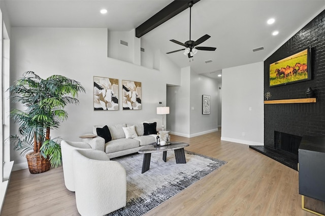 living room with a ceiling fan, wood finished floors, a fireplace, beamed ceiling, and baseboards
