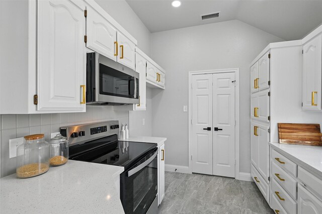 kitchen featuring stainless steel appliances, white cabinets, decorative backsplash, vaulted ceiling, and baseboards