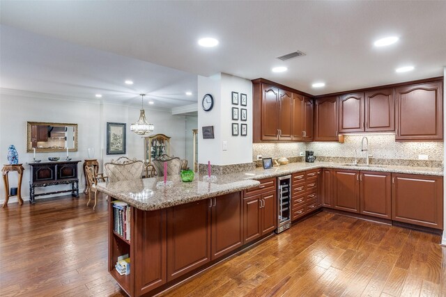 kitchen featuring a sink, wine cooler, dark wood-style flooring, light stone countertops, and crown molding
