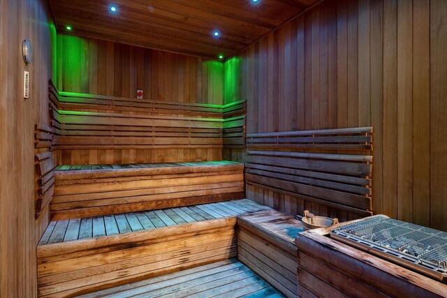 relaxing sauna featuring wood walls, wooden ceiling, and recessed lighting
