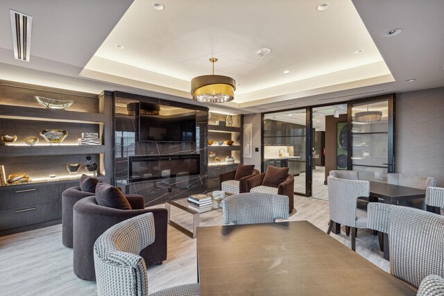 dining room with a raised ceiling and light wood-style flooring