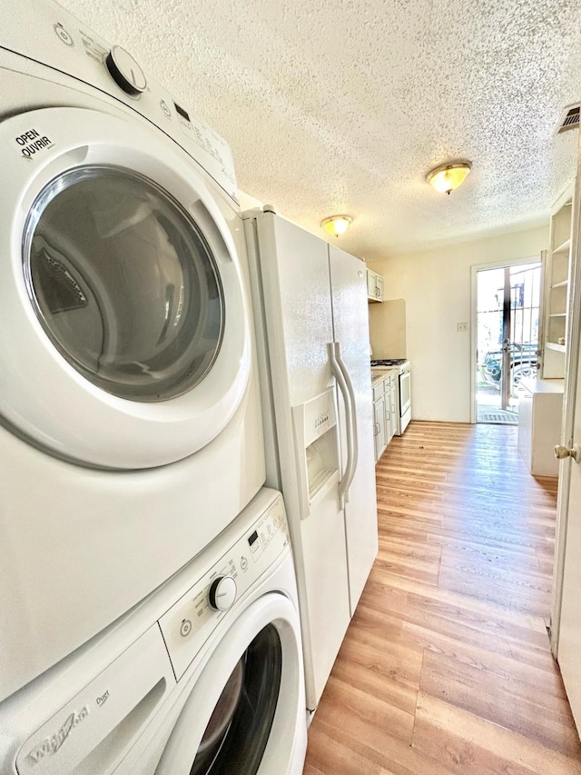 3601 Avenue N, Fort Worth, TX 76105 - washroom with stacked washer and clothes dryer, light wood finished floors, and a textured ceiling