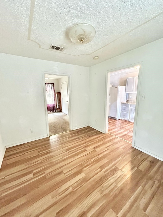 3601 Avenue N, Fort Worth, TX 76105 - unfurnished room featuring a textured ceiling, light wood-type flooring, and baseboards