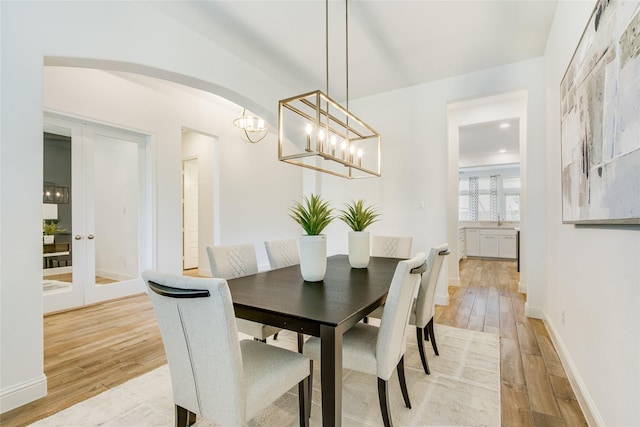 2406 Capitol Pl, Melissa, TX 75454 - dining area with light wood-type flooring, arched walkways, a chandelier, and baseboards