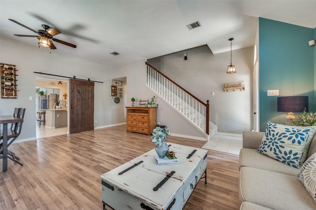 1361 Daffodil Ln, Lewisville, TX 75077 - living room with a barn door, a ceiling fan, stairway, light wood-style floors, and baseboards