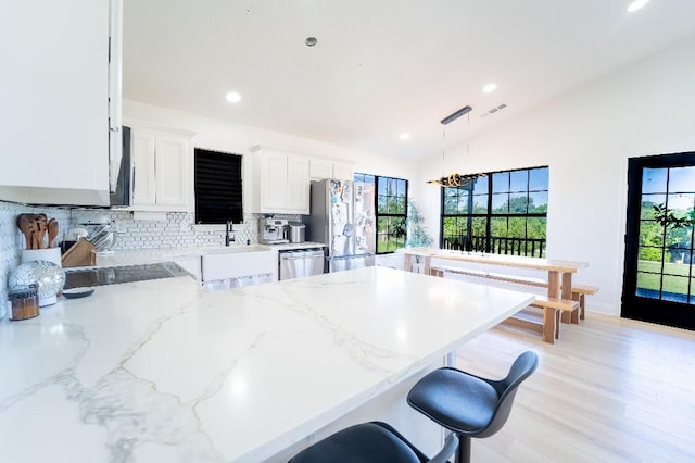 9471 Twin Creeks Cir, Anna, TX 75409 - kitchen featuring stainless steel appliances, a peninsula, decorative backsplash, lofted ceiling, and a kitchen breakfast bar