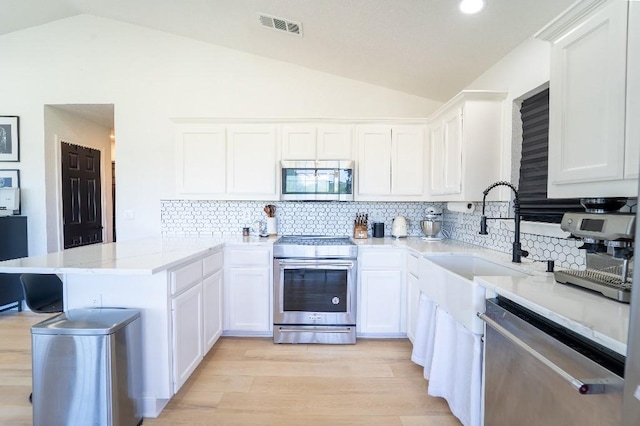 9471 Twin Creeks Cir, Anna, TX 75409 - kitchen featuring stainless steel appliances, lofted ceiling, a peninsula, decorative backsplash, and white cabinetry